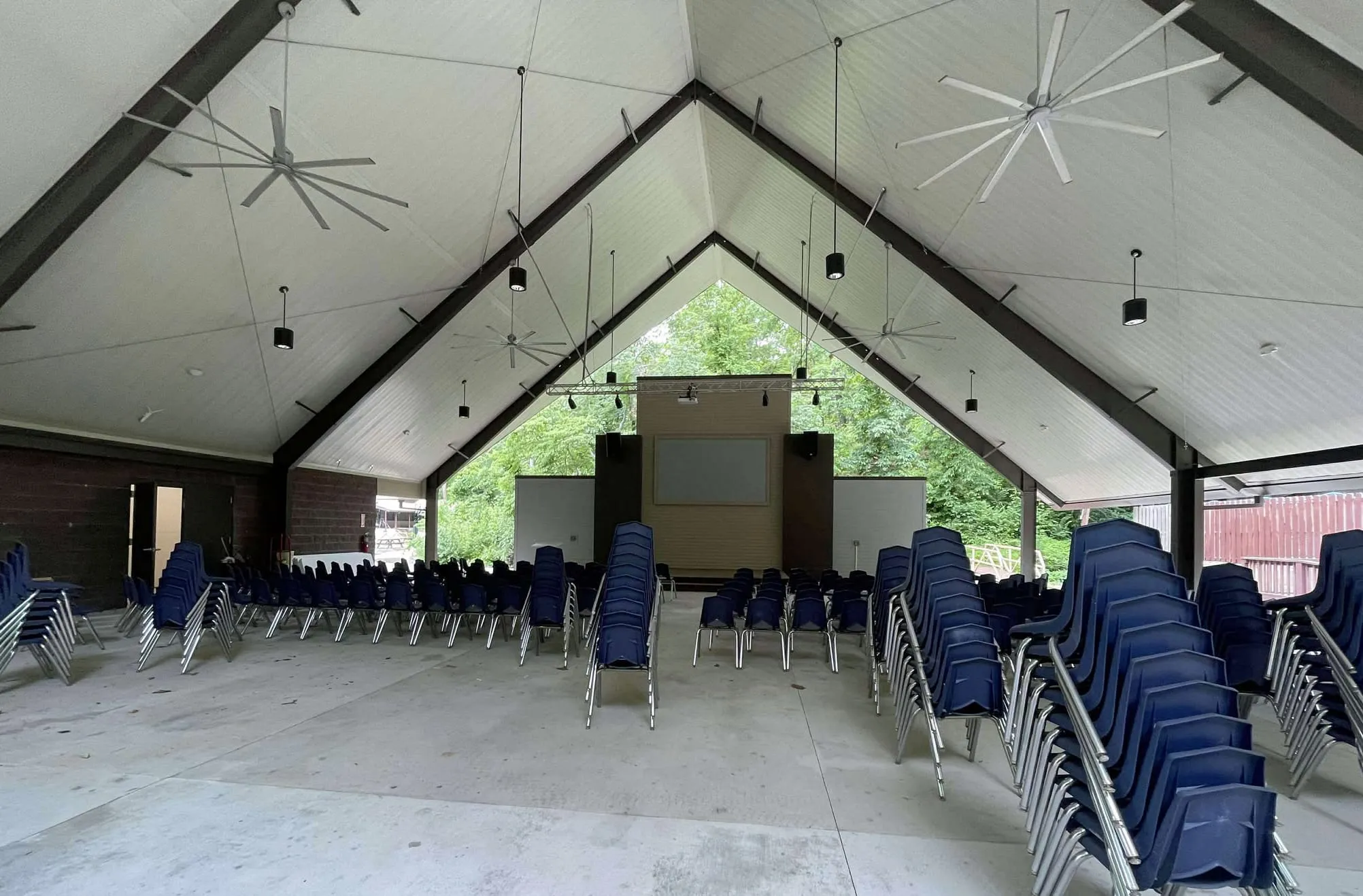 The covered outdoor pavilion at Green Valley Bible Camp, set with chairs and large ceiling fans, used as the crating area